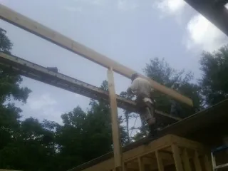Carpenter setting a ridge beam over a new addition frame — Ice Dam Removal by Roofing Brothers in Drury