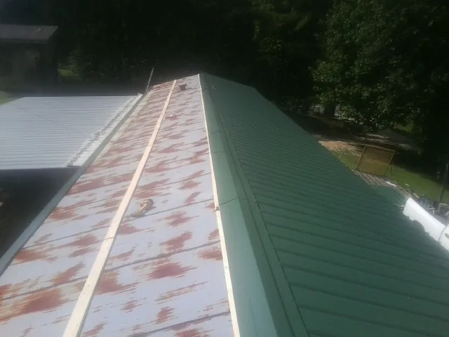 Old rusted panels beside newly installed green metal roofing — Wind Damage Roof Repair by Roofing Brothers in Drury
