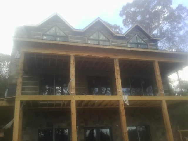 Dormers and porch framing on a large log home under construction — Roof Coating work by our crew in Drury