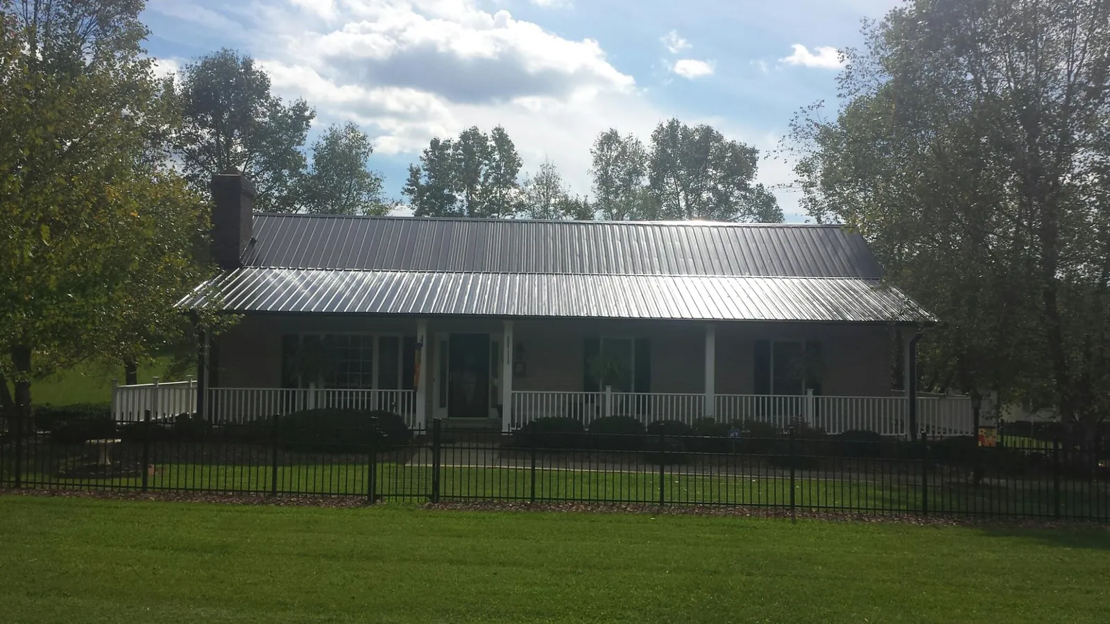 Gray metal roof on a brick ranch with a full width front porch — Gutter Guard Installation work by our crew in Drury