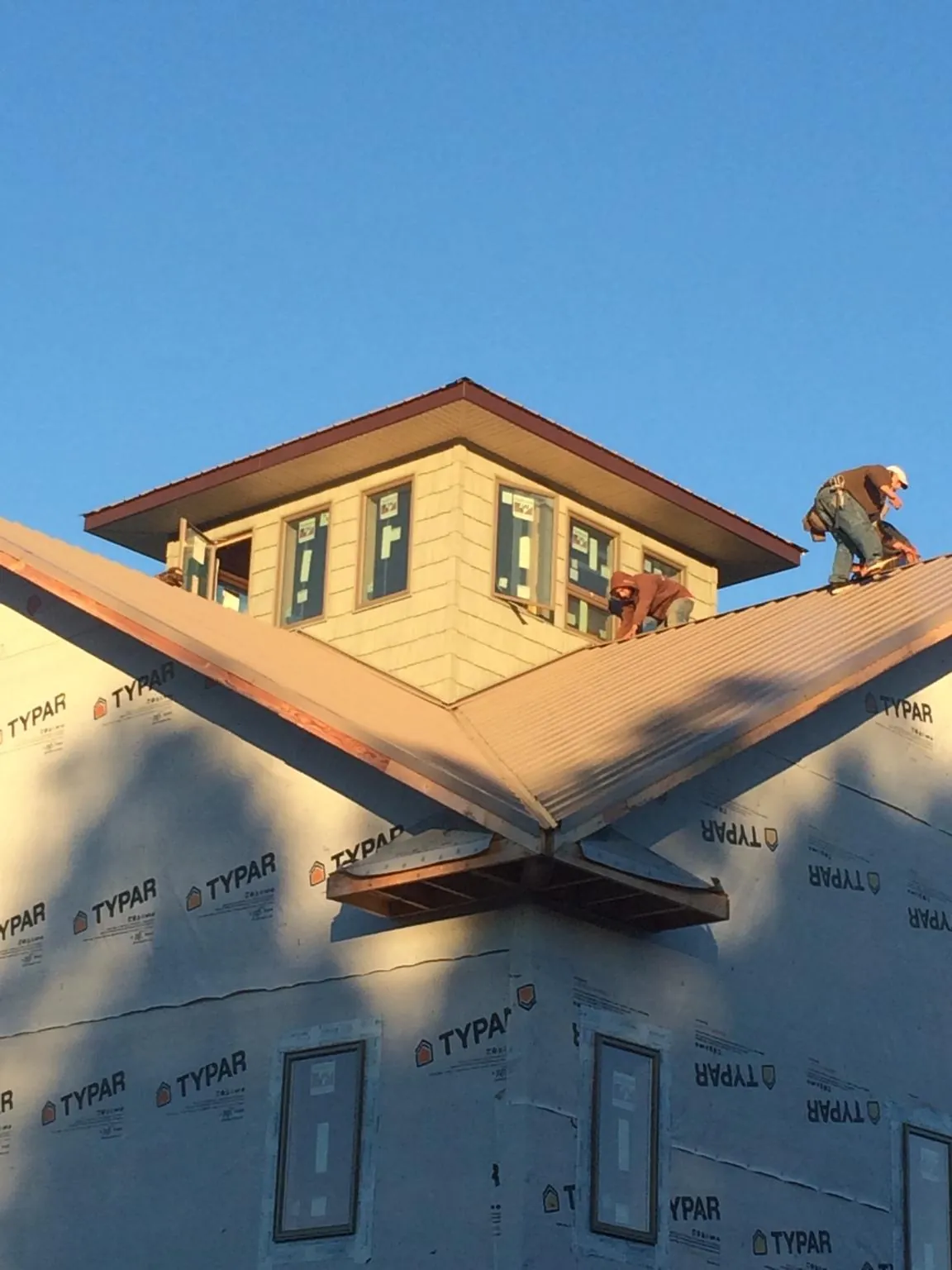 Roofers working around a rooftop cupola on a new metal roof at sunset — Roof Waterproofing in Drury by Roofing Brothers